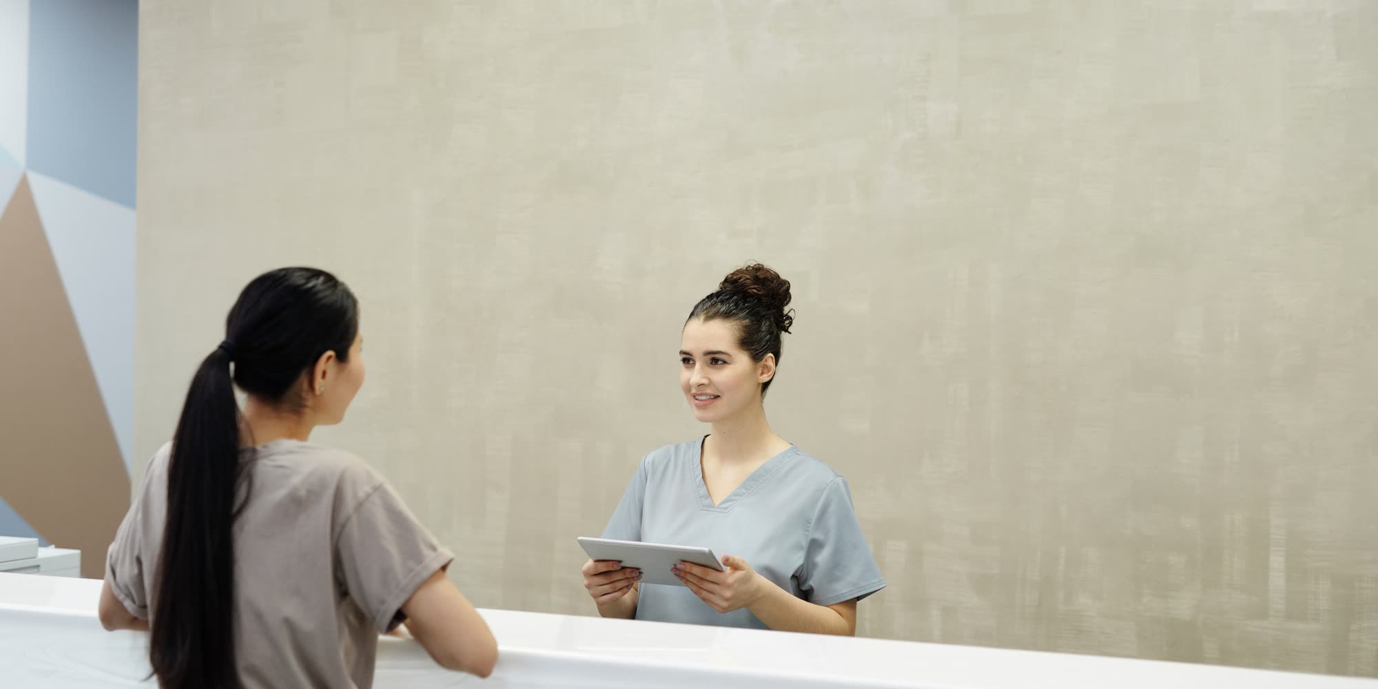 Patient och receptionist vid disken