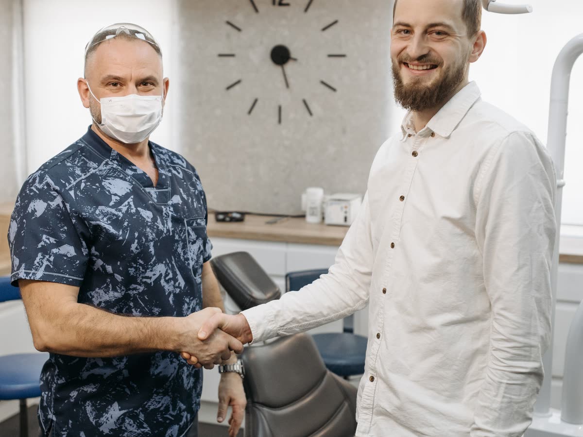 Behandlare och patient tar i hand i ett behandlingsrum